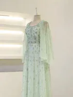 Luxurious pale green embroidered gown with intricate beadwork and sheer cape details, perfect for special occasions and events.