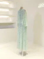 A stunning mint green dress with sequins and layered fabric, perfect for special occasions, displayed on a mannequin in a modern boutique setting.
