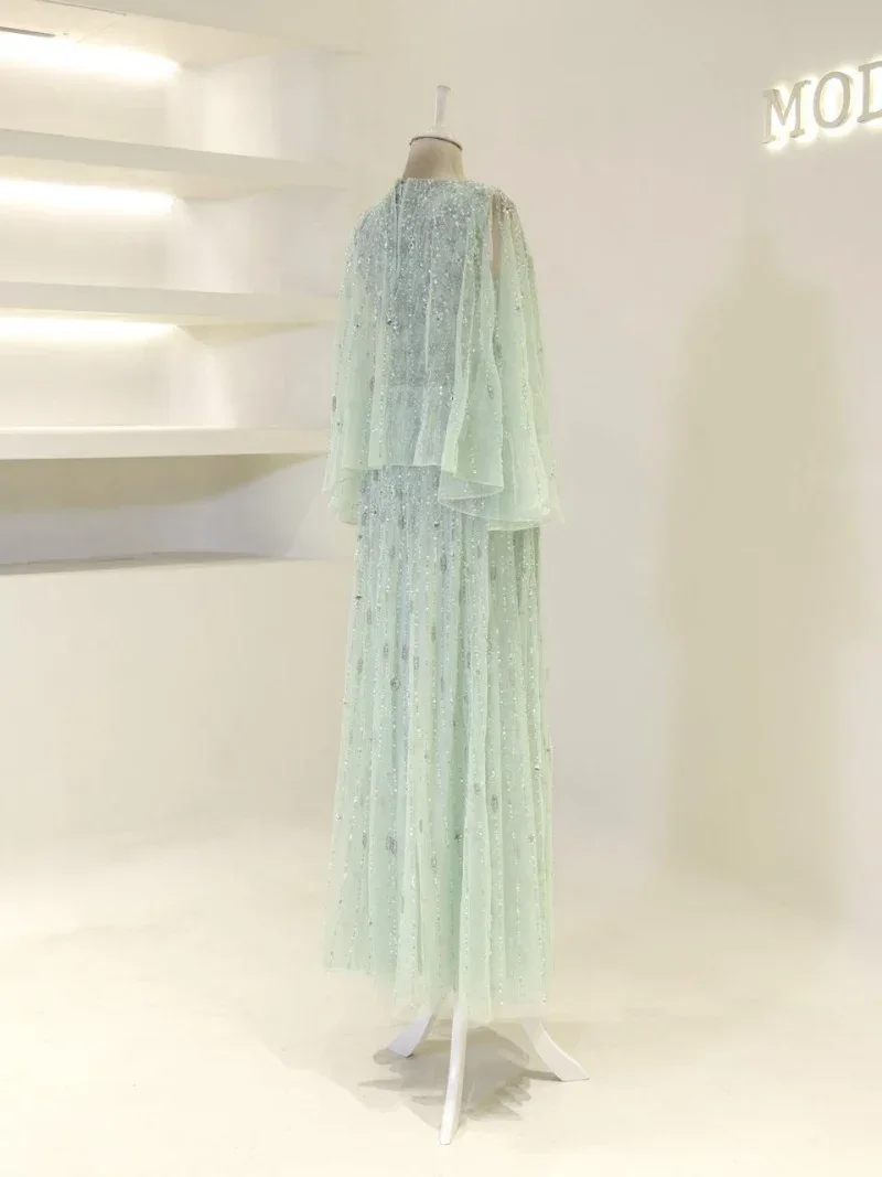 A stunning mint green dress with sequins and layered fabric, perfect for special occasions, displayed on a mannequin in a modern boutique setting.