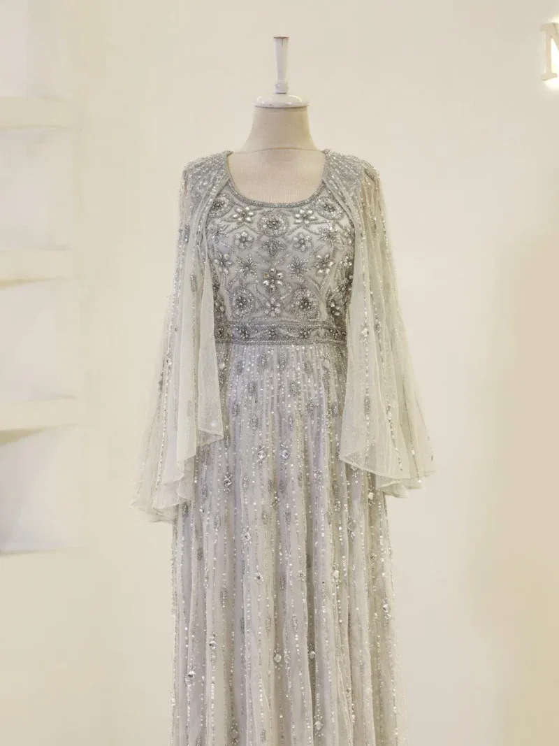 Luxurious white gown featuring intricate embroidery and beadwork, perfect for special occasions or weddings. Made with high-quality fabrics and craftsmanship for a stunning appearance.