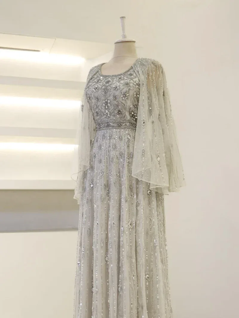 Luxurious white wedding gown with intricate silver bead embroidery, sequins, and delicate chiffon cape, perfect for special occasions and bridal wear.