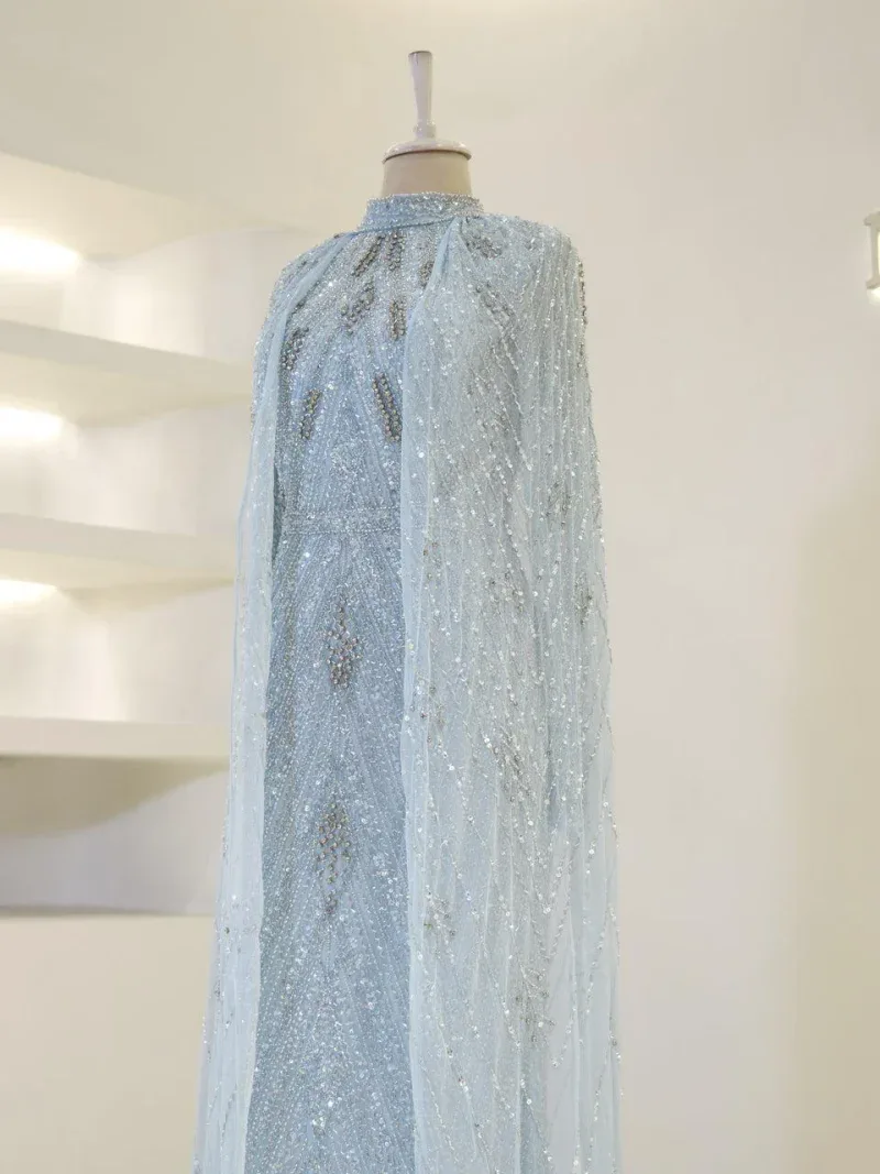 Stunning light blue bridal cape with intricate beadwork, sequins, and embroidery designed for special occasions or weddings. Made from delicate, high-quality fabric for a luxurious look.
