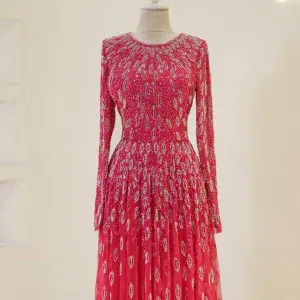Stunning pink evening gown featuring intricate embroidery and sequins, long sleeves, and a flowing skirt perfect for formal occasions or special events.
