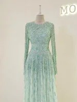 Lush beaded formal dress with intricate embellishments, long sleeves, and flowing skirt perfect for special occasions or parties.