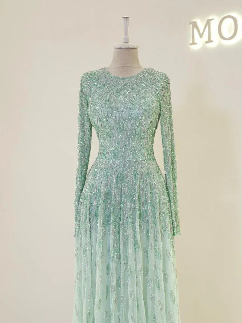 Lush beaded formal dress with intricate embellishments, long sleeves, and flowing skirt perfect for special occasions or parties.