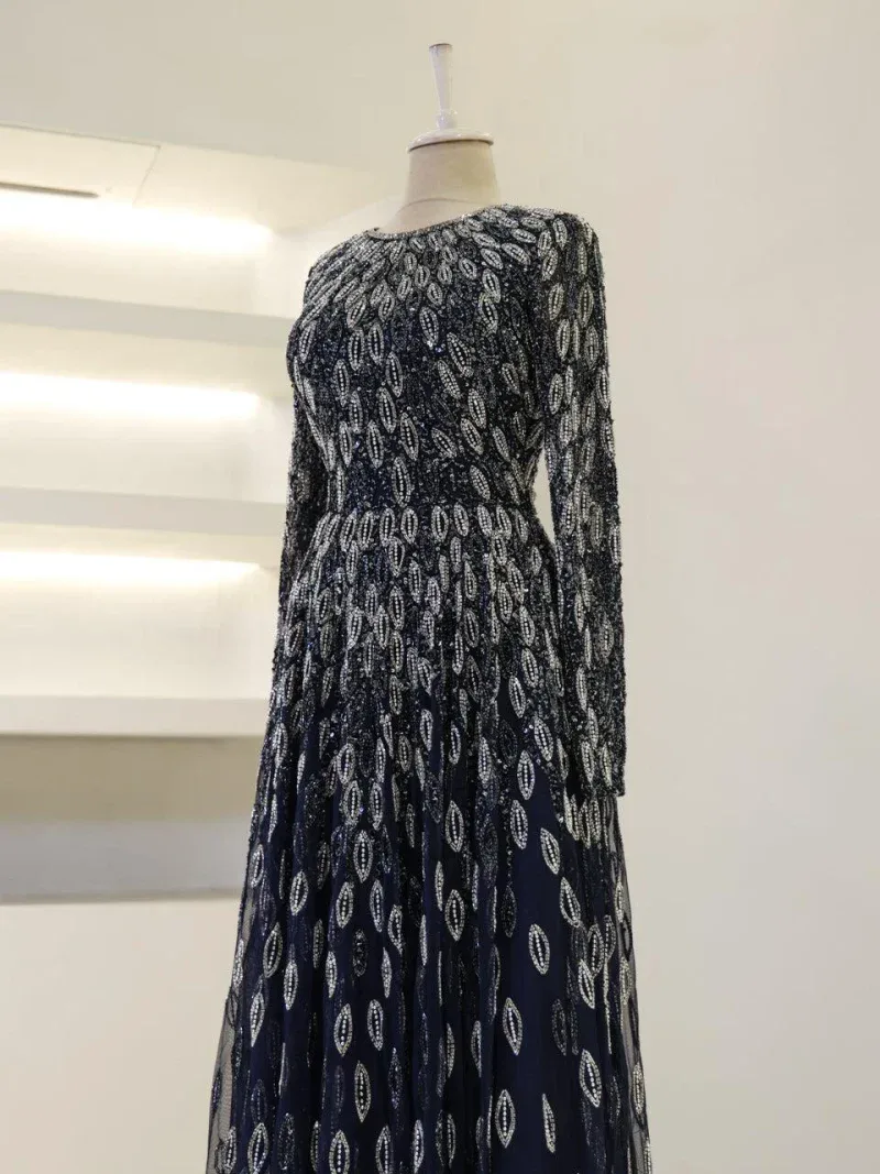 A stunning navy blue dress featuring intricate silver embroidery, long sleeves, and a flowing skirt, perfect for formal occasions.