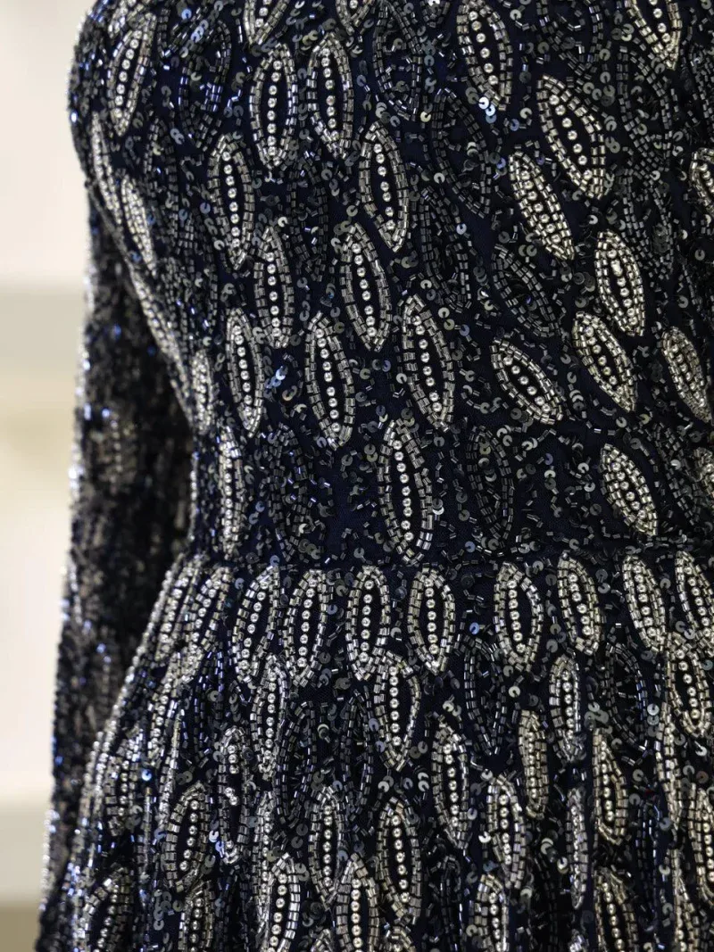 A stunning black dress adorned with intricate silver beadwork creating a luxurious and eye-catching pattern perfect for evening wear and special occasions.