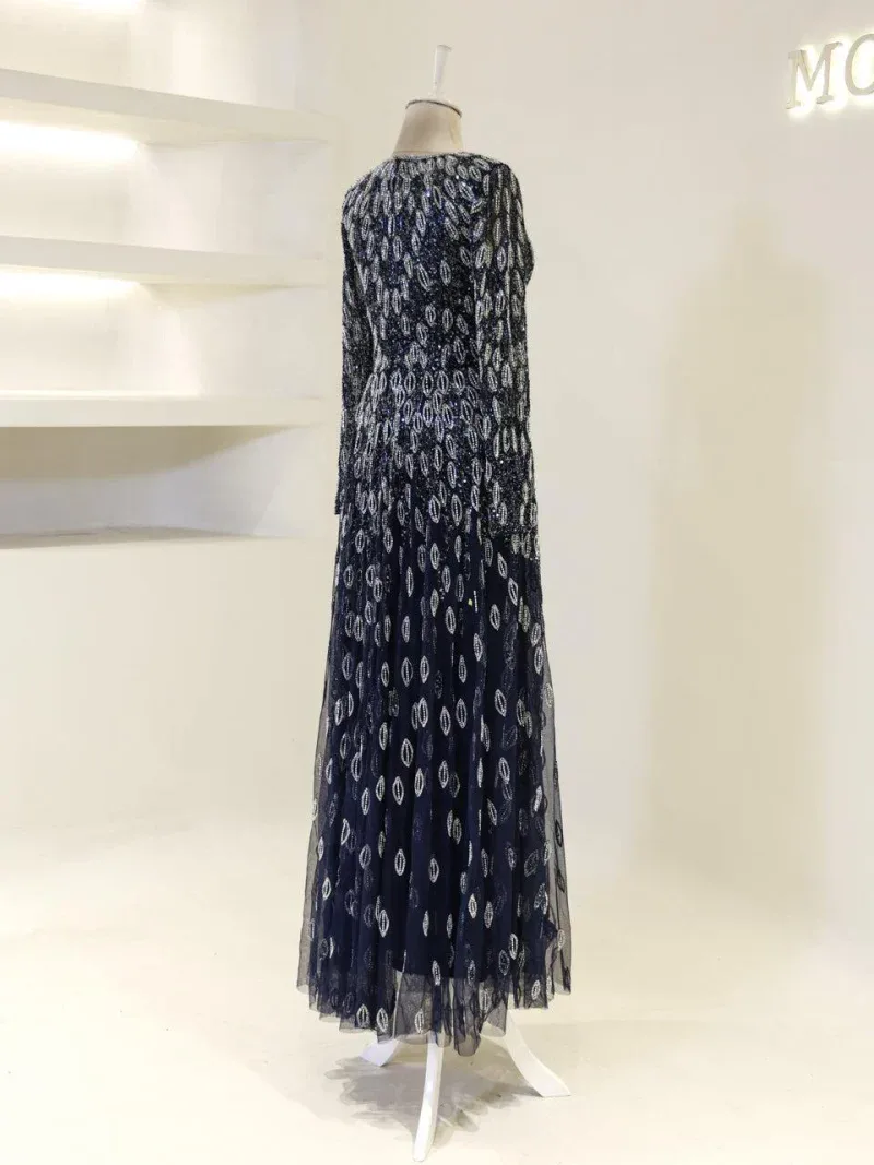 A stunning navy blue maxi dress with detailed silver leaf embroidery, ideal for elegant events and celebrations, showcased on a mannequin in a contemporary retail setting.