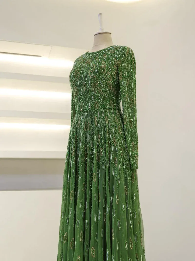 Stunning long green dress adorned with shimmering sequins, perfect for special occasions or evening events. Features intricate detailing and a flowing silhouette for a glamorous look.