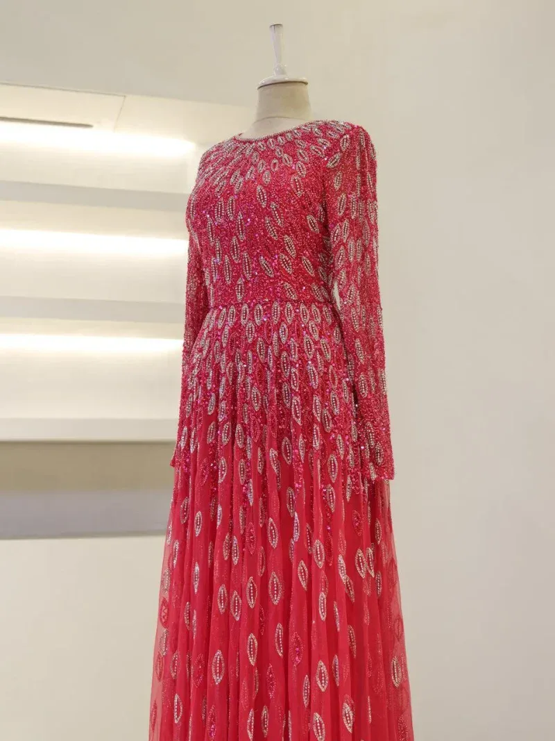 Luxurious red dress with intricate sequin embellishments, long sleeves, and flowing skirt, perfect for special occasions or parties.