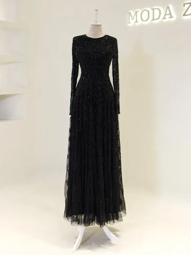 A stunning black evening gown featuring intricate sequins, long sleeves, and a flowing tulle skirt perfect for formal events and special occasions.
