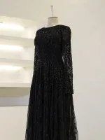 Luxurious black evening gown with intricate beadwork, long sheer sleeves, and flowing skirt, perfect for formal occasions and special events.