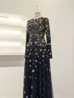 A stunning long dress with intricate floral embroidery in pink, green, and white on a navy blue background. Features long sleeves and a fitted waist, perfect for formal occasions.