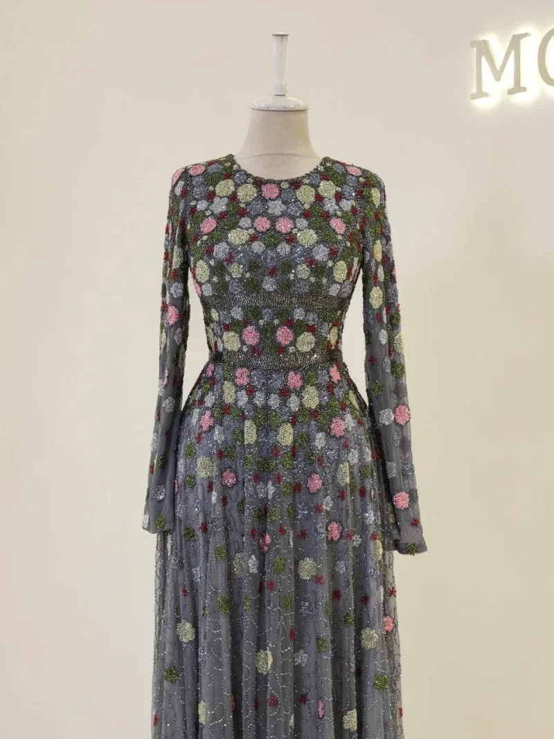 Impressive long-sleeve dress featuring intricate floral embroidery with vibrant pink, green, and silver accents on sheer fabric. Perfect for special occasions or fashion statements.