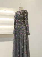 An exquisite long dress featuring intricate floral embroidery with colorful embellishments on a sheer, flowing fabric for a stylish, sophisticated look.