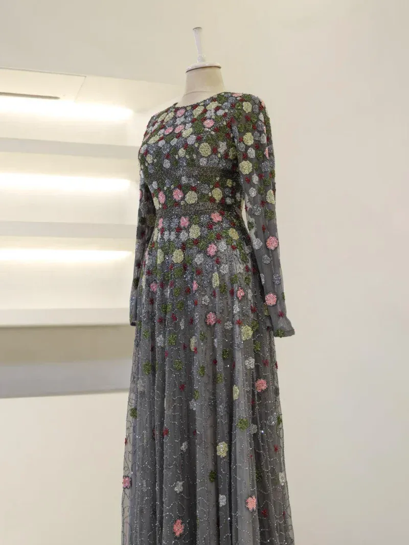 An exquisite long dress featuring intricate floral embroidery with colorful embellishments on a sheer, flowing fabric for a stylish, sophisticated look.