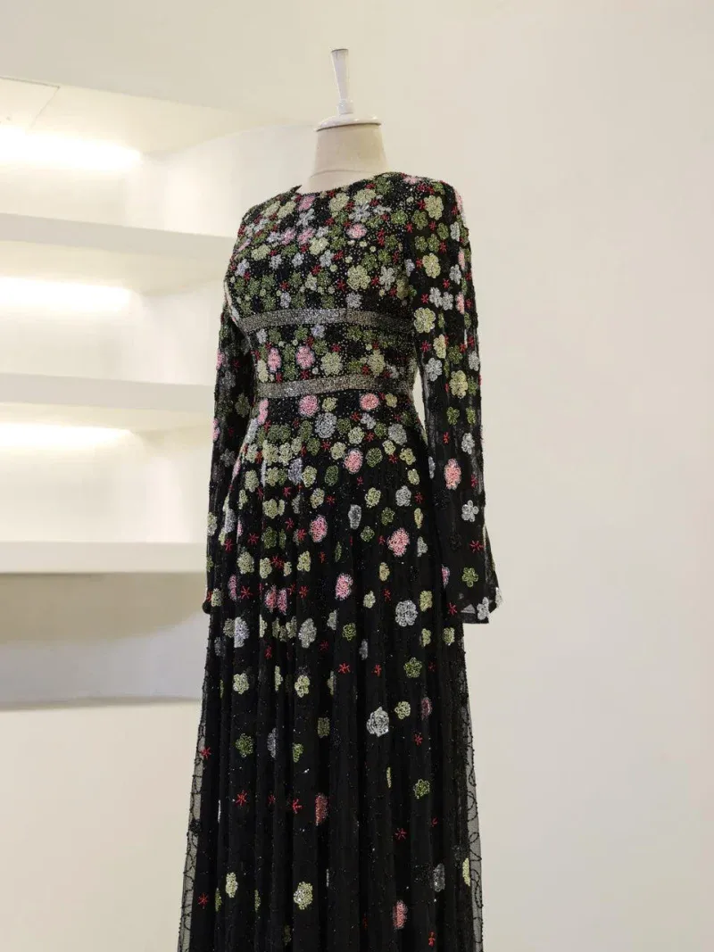 Stunning black dress with multicolored floral embroidery, long sleeves, and a flowing skirt perfect for special occasions or evening wear.