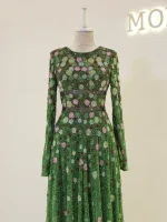 Luxurious green dress adorned with intricate floral embroidery, featuring long sleeves and a flowing skirt, perfect for special occasions or celebrations.