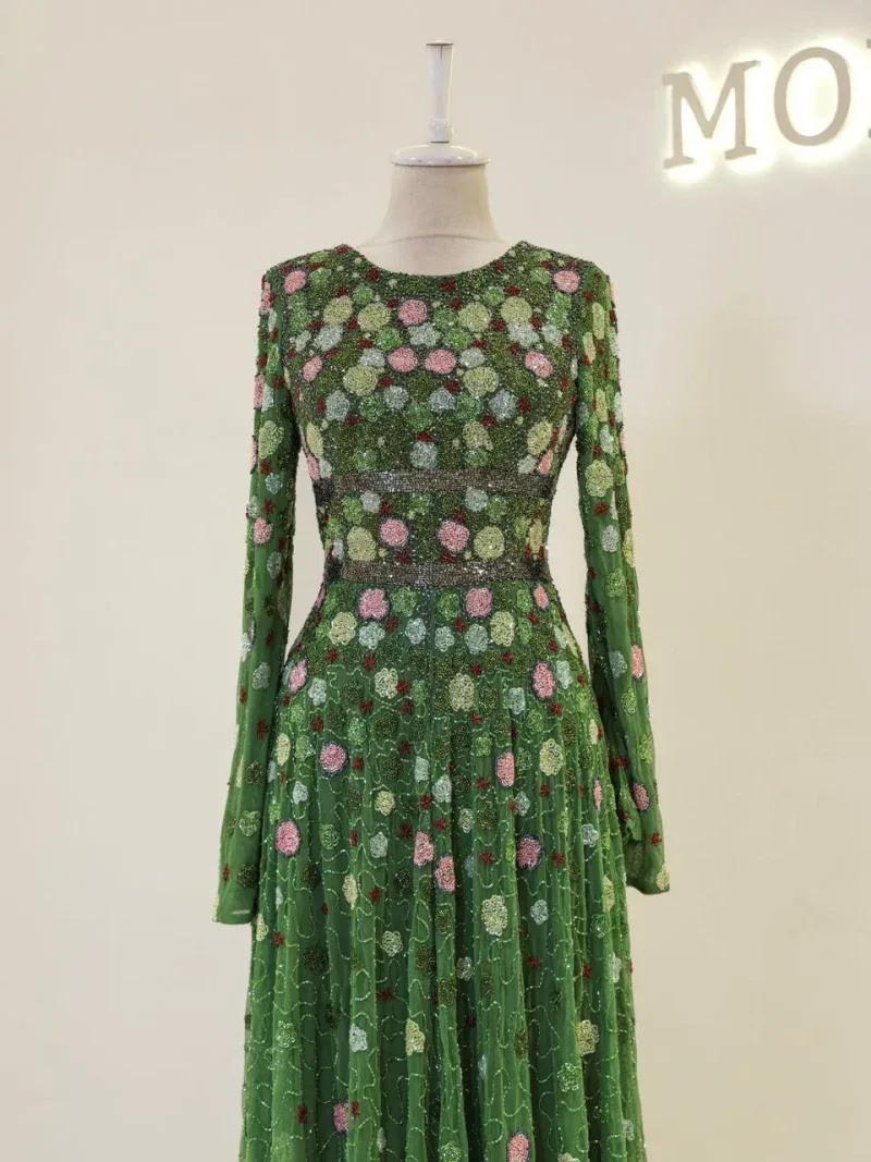 Luxurious green dress adorned with intricate floral embroidery, featuring long sleeves and a flowing skirt, perfect for special occasions or celebrations.