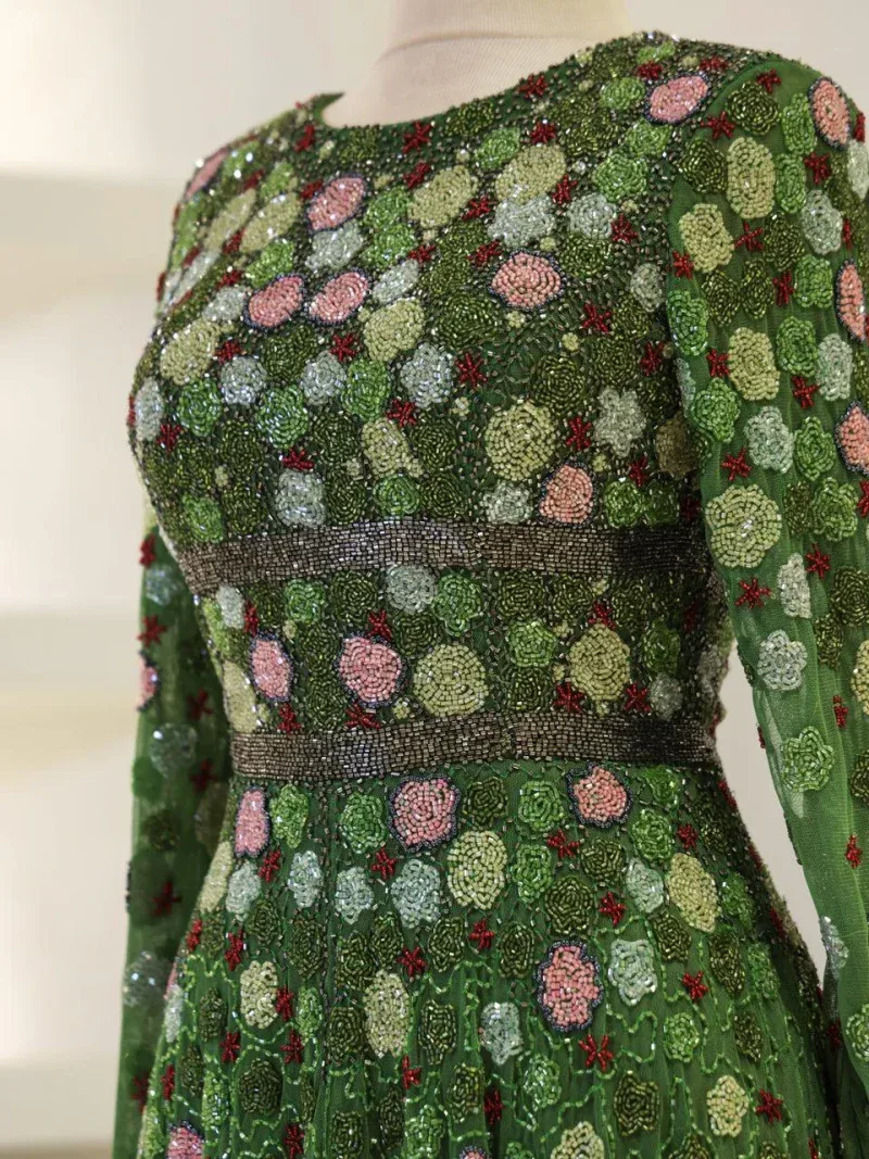 Intricate green floral beaded dress with pink and red accents, featuring detailed embroidery and shimmering embellishments, perfect for special occasions and cultural celebrations.