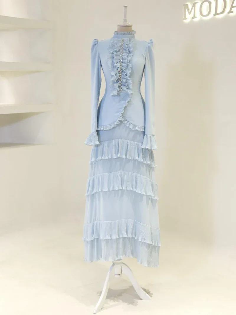Beautiful long blue dress with ruffle embellishments, high neckline, fitted waist, and layered pleated skirt, perfect for formal occasions or elegant events.
