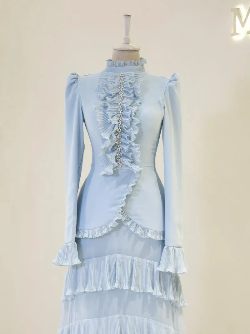 A stunning white Ottoman-inspired dress featuring intricate ruffle and pleated details, long sleeves with ruffle cuffs, and a fitted silhouette, perfect for elegant occasions.