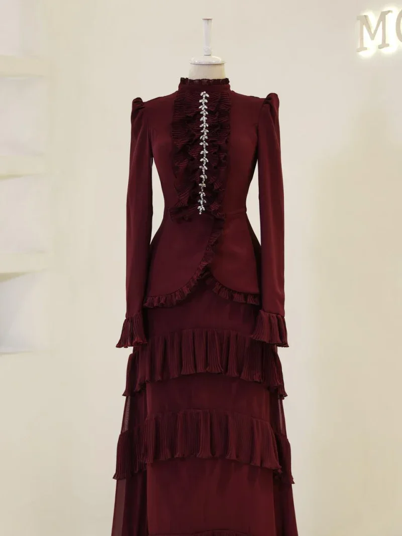 Stunning burgundy dress featuring intricate ruffle details, long sleeves, puff shoulders, and decorative embellishments down the front, perfect for formal occasions or stylish events.