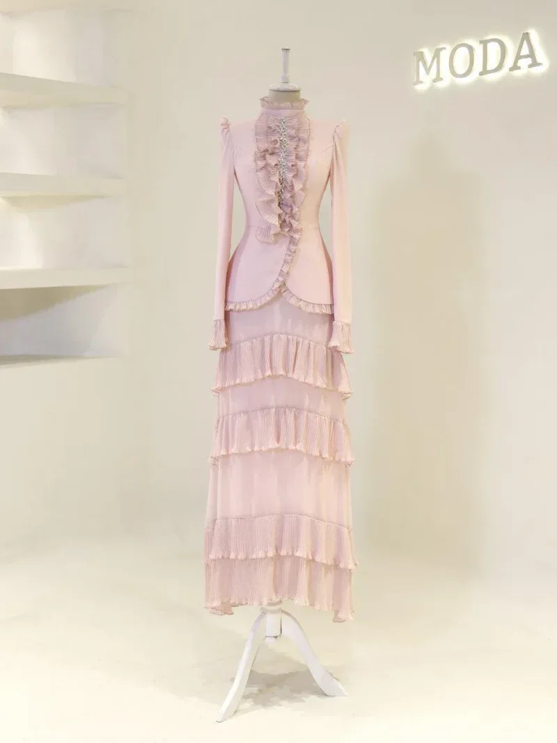 Stylish pink dress with layered ruffles and long sleeves showcased on a mannequin in a modern fashion boutique.