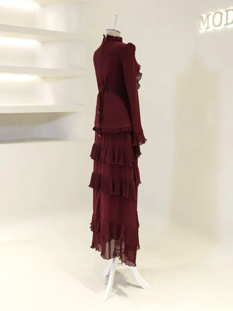 A stylish, deep burgundy dress featuring tiered ruffles and pleats, perfect for sophisticated occasions and evening wear.
