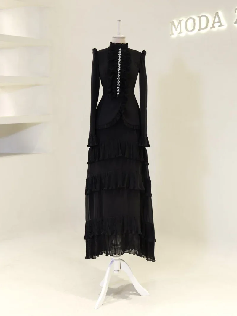 A sophisticated black Victorian-inspired dress featuring ruffled details, long sleeves, and layered pleated skirt, perfect for formal occasions or themed events.