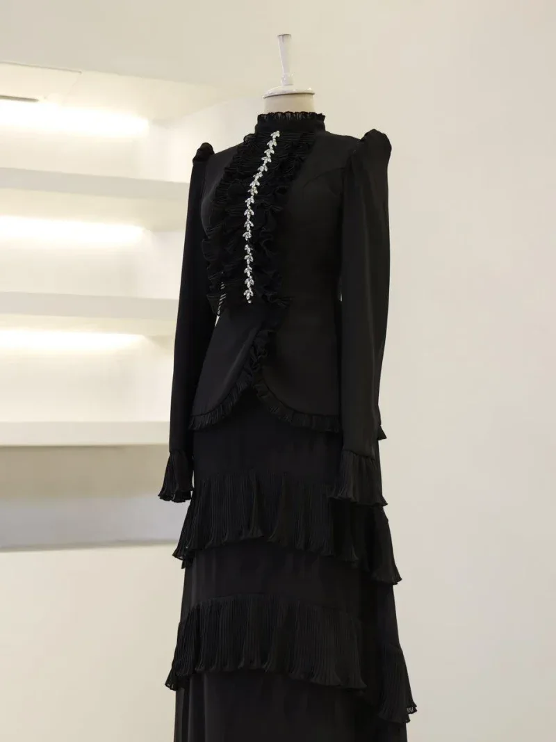 Stylish black dress featuring multiple ruffled layers and intricate jewelry embellishments on the front, perfect for formal occasions or evening events.