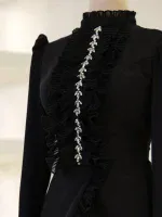 Beautiful black evening dress adorned with ruffled fabric and shiny crystal jewelry, ideal for parties, events, or special nights out. The high collar and detailed embellishments add a touch of sophistication and elegance to the attire.