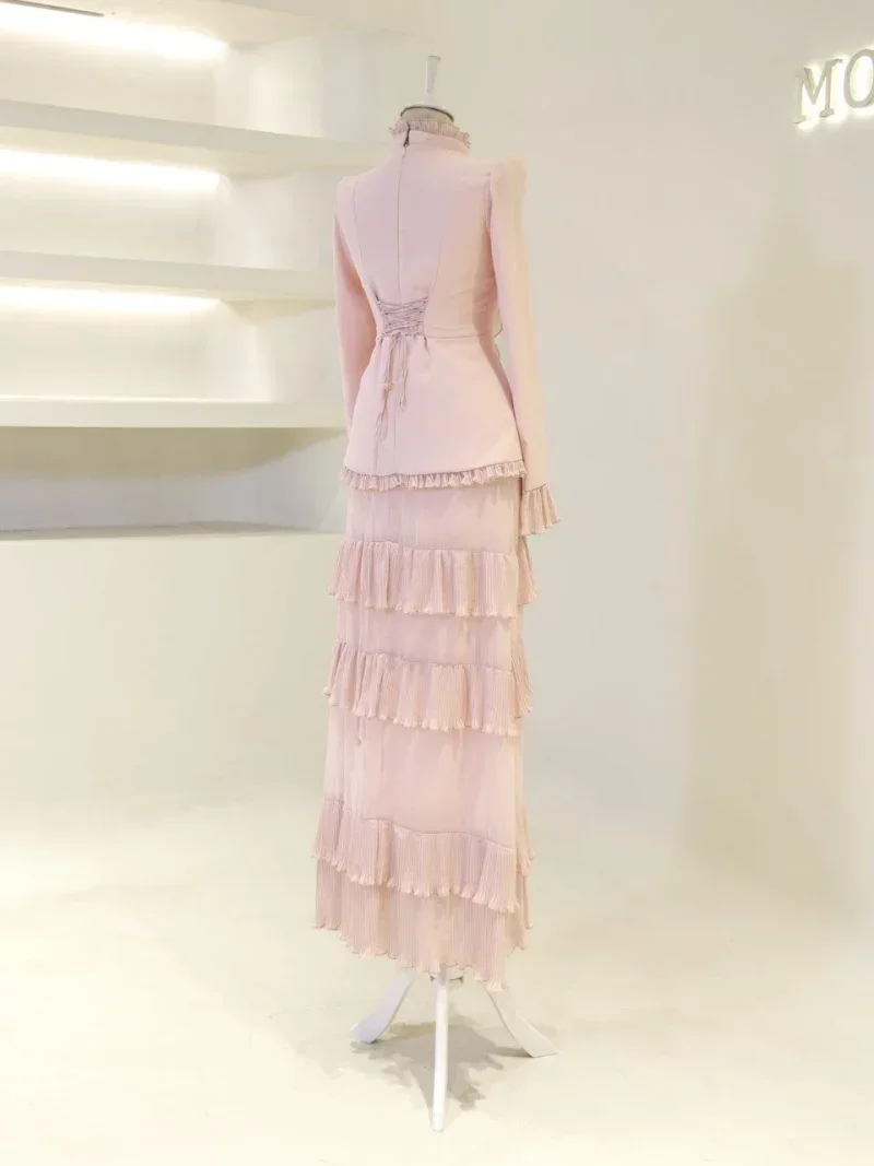 Pink tiered maxi dress displayed on a mannequin, featuring frilled layers and a high neckline. Perfect for formal events or special occasions with a stylish and feminine design.