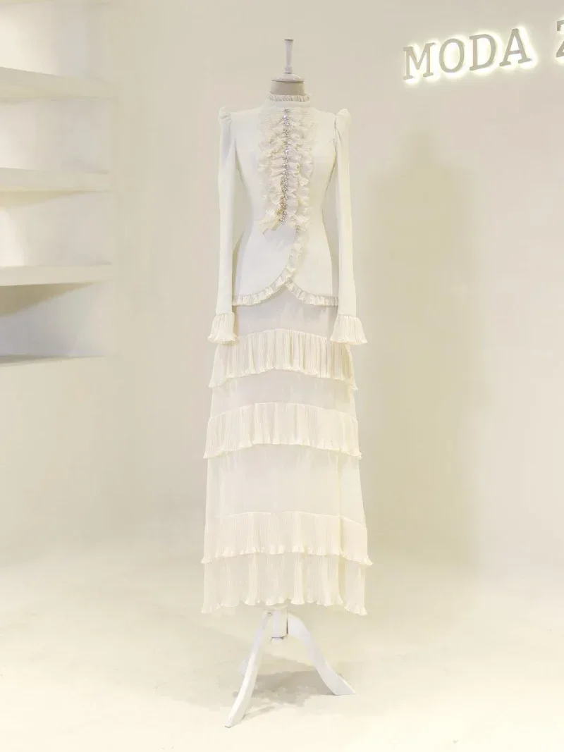 Stylish ivory dress with layered ruffles and pleats, perfect for formal occasions or fashion-forward events. Features long sleeves and intricate detailing, available for quick shipping from Turkey.