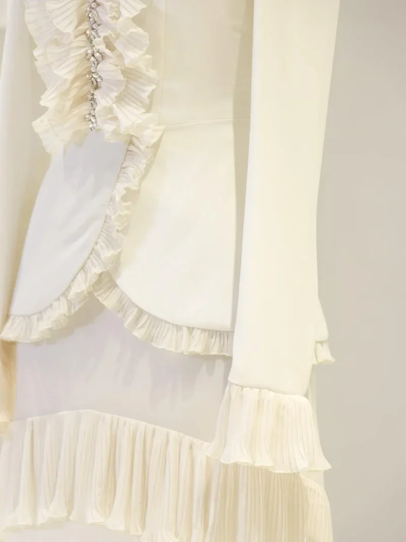 Highly detailed cream-colored dress with intricate ruffle accents and sparkling embellishments, ideal for special occasions or formal events.