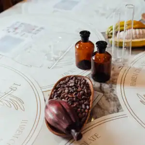 1. Assorted baking ingredients with cocoa beans, amber bottles, and test tubes on a marble table for baking or confectionery preparation.