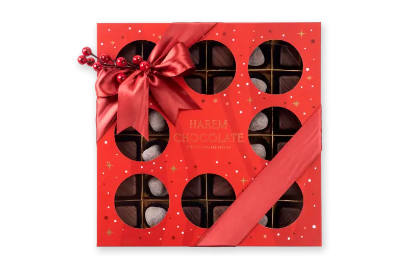 Deluxe holiday chocolate box with festive red ribbon and berry decoration, featuring assorted chocolates and truffles from Harem Chocolate, perfect for gift-giving during festivities.