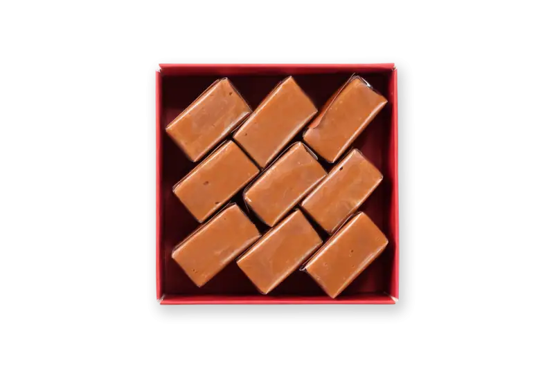Rich caramel fudge pieces in a red gift box, showcasing traditional Turkish sweet treats with smooth, glossy texture. Perfect for gifting or enjoying authentic Turkish confections.
