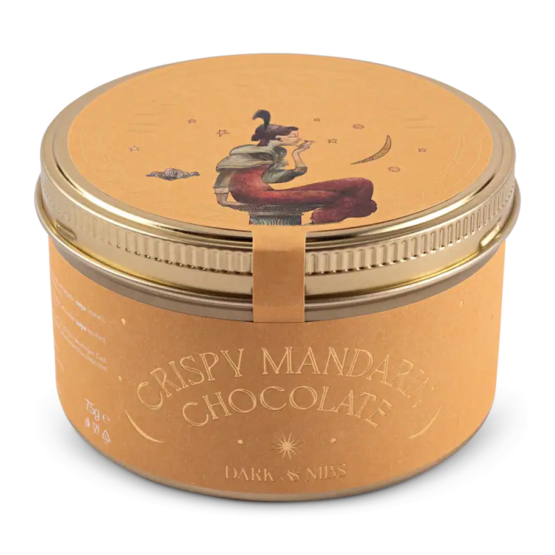 Elevated image of crispy mandarin chocolate tin with artistic illustration of a woman reading, featuring warm tones and elegant design. Perfect for gift or personal indulgence.