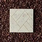 Cream-colored chocolate bar with speckles on a bed of roasted coffee beans, highlighting Turkish craftsmanship and rich flavors.