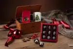 Deluxe Turkish chocolates and Christmas-themed gifts in a woven basket, perfect for holiday celebrations, with festive decorations and a cozy fur blanket on a rustic wooden surface.