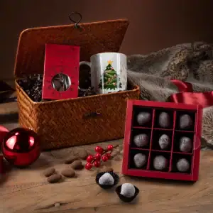 Deluxe Turkish chocolates and Christmas-themed gifts in a woven basket, perfect for holiday celebrations, with festive decorations and a cozy fur blanket on a rustic wooden surface.