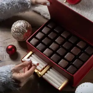 Luxurious box of assorted chocolates with Christmas ornaments on wooden surface, holiday gift idea from Turkey, fast shipping available.