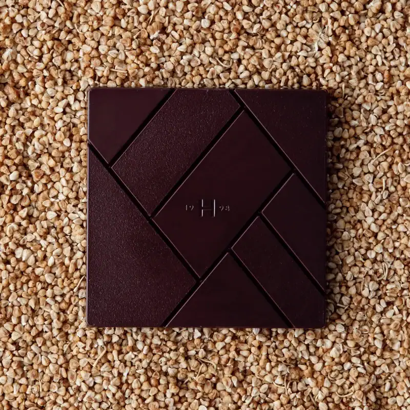 Dark chocolate packaging on a bed of buckwheat grains, highlighting Turkish gourmet specialty foods with fast shipping from Turkey.