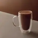 Rich Turkish hot chocolate served in a clear double-walled glass mug for a cozy beverage experience. Perfect for warming up anytime.