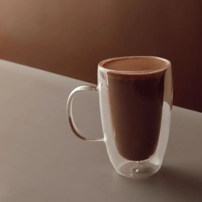 Rich Turkish hot chocolate served in a clear double-walled glass mug for a cozy beverage experience. Perfect for warming up anytime.