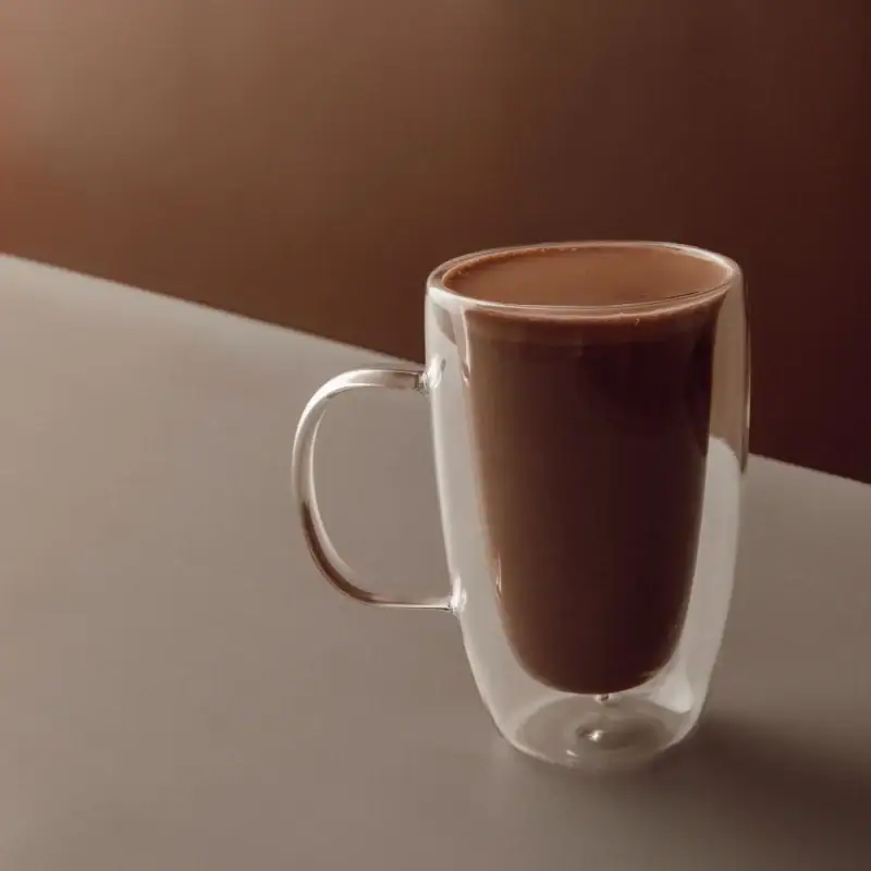 Rich Turkish hot chocolate served in a stylish double-walled glass mug on a modern minimalist background. Perfect for cozy delights and quick comfort.