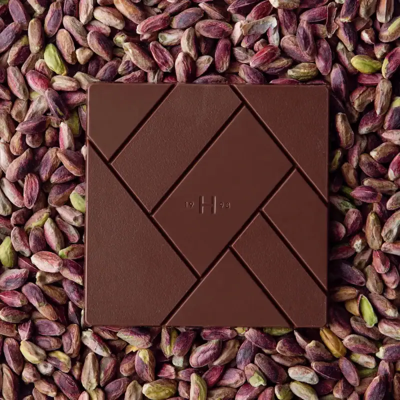 Smooth milk chocolate bar on pistachio nuts, luxurious confectionery, premium quality, handcrafted, Turkish chocolate, sweet, delicious, snack, gourmet treat, artisanal chocolate, rich flavor.