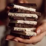 Cream and dark chocolate chunks stacked in a person's hand, showcasing Turkish chocolates for a delightful treat.