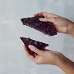 Rich dark chocolate bar with dried blueberries, hand-held and ready to enjoy, showcasing Turkish quality confections.